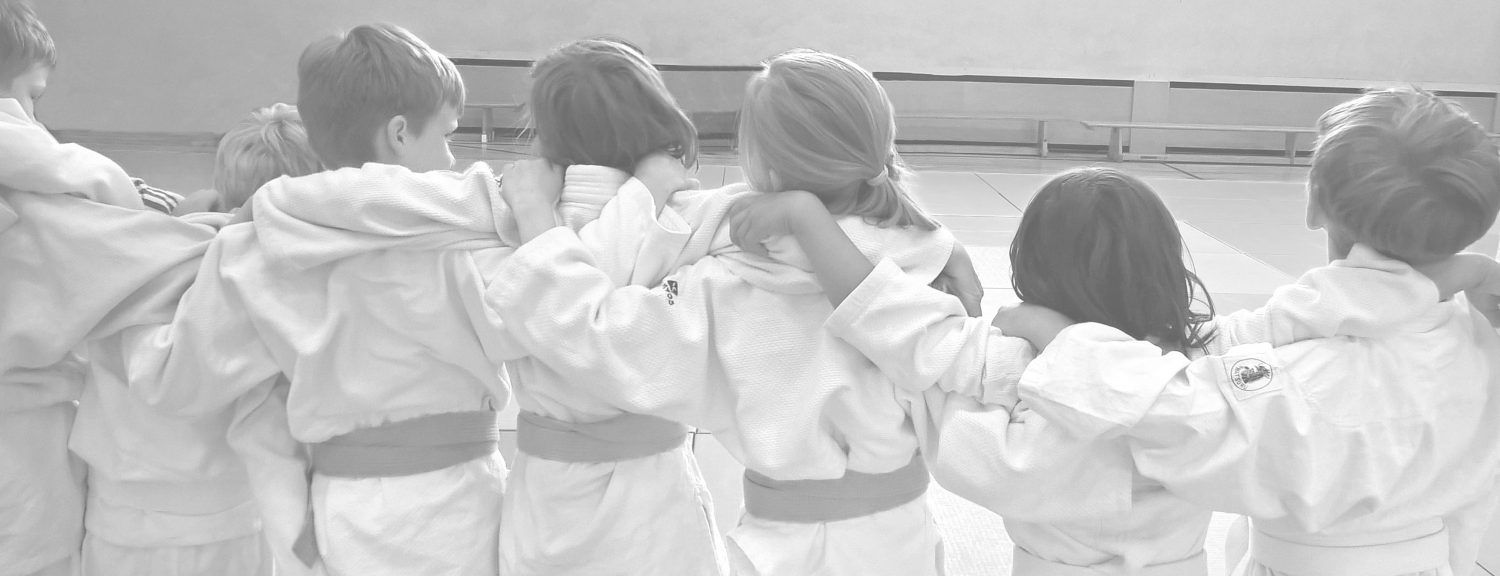 Judokas im Kreis, Arm in Arm, von hinten fotografiert
